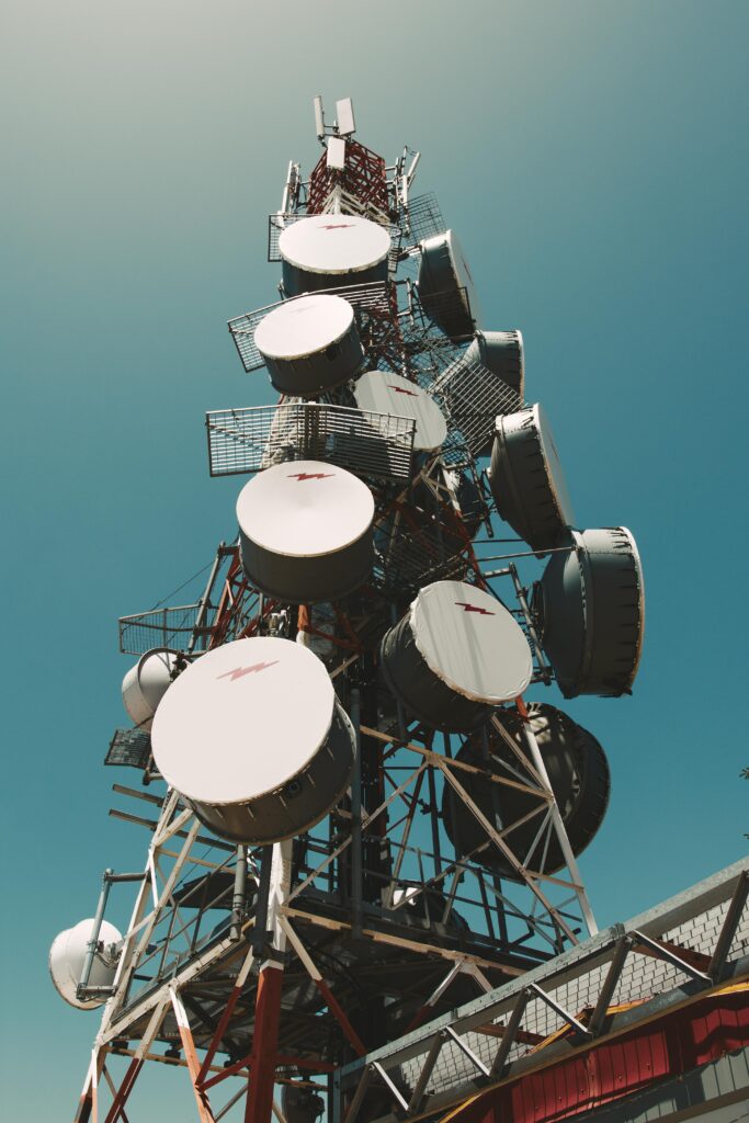 A towering communication tower with satellite dishes under a clear blue sky, symbolizing telecommunications.